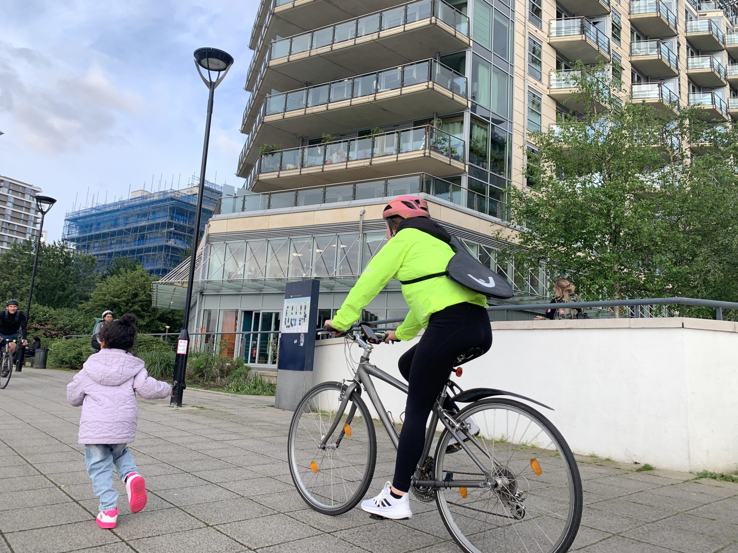 Two people exercising - A small child running and an adult on a bike in an urban environment