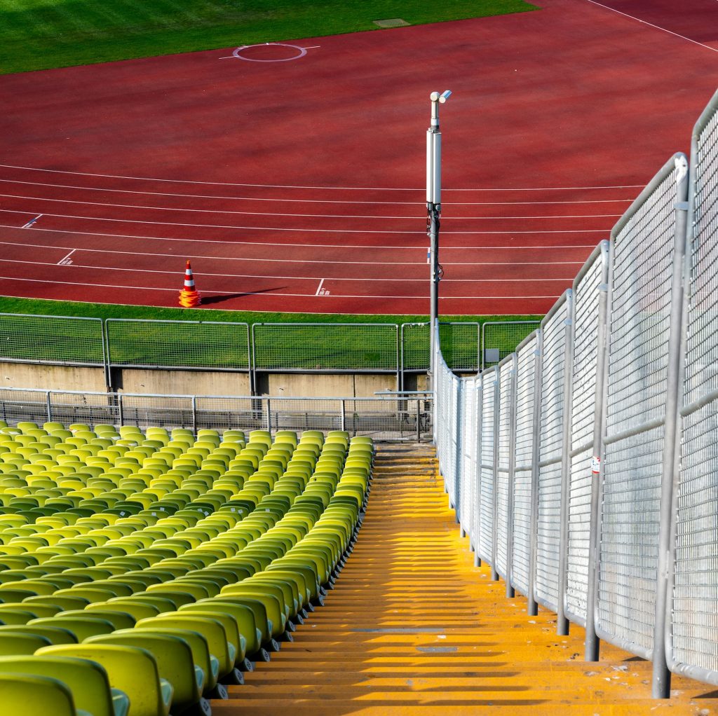 View down steps next to seating, looking to an athletics track, showing accessibility obstacles.